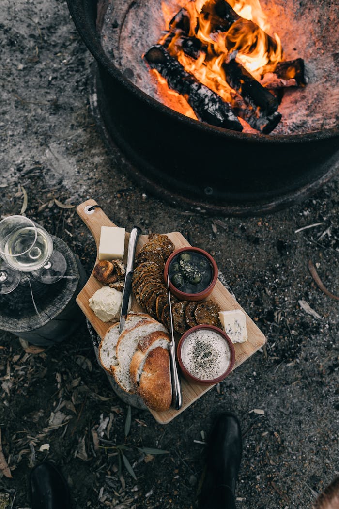Crop person near bonfire with food
